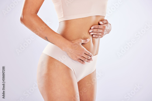 Woman, hand on stomach and body for healthy lifestyle in studio as motivation for weight loss, diet or fitness. Female on a white background for gut health, wellness or skin care in underwear