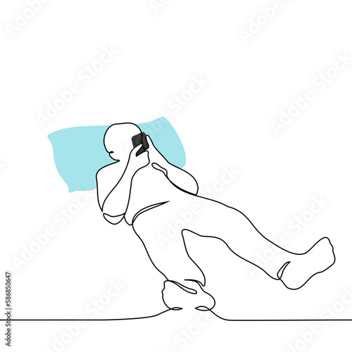 man lies in bed with his head on pillows and a phone in his hands - one line drawing vector. concept internet addiction, addiction to social networks