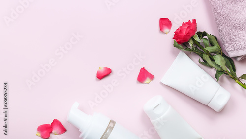 Composition with skin care products and rose flowers on pink table background. Copy space