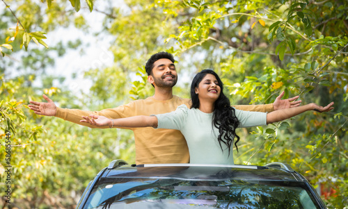 Картината върху платно Happy smiling couple feeling nature fresh air by stretching arms on car sunroof