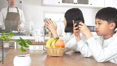 ダイニングでゲームをする子供と料理をする男性