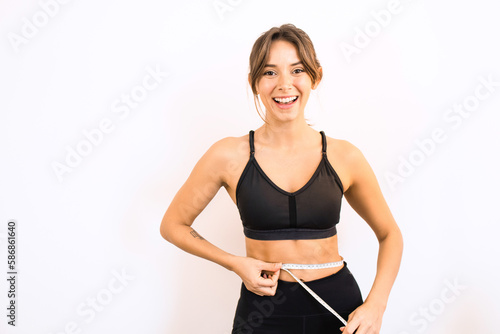 Young Happy Sporty Woman Holding a Measuring Tape Feeling Happy with Weight Loss Muscle Gain © Lais