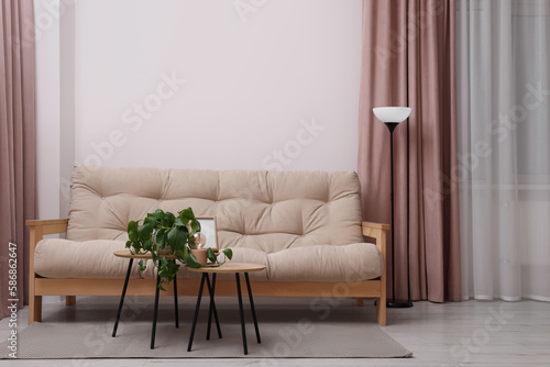 Comfortable sofa and houseplant on coffee table in light room. Interior design