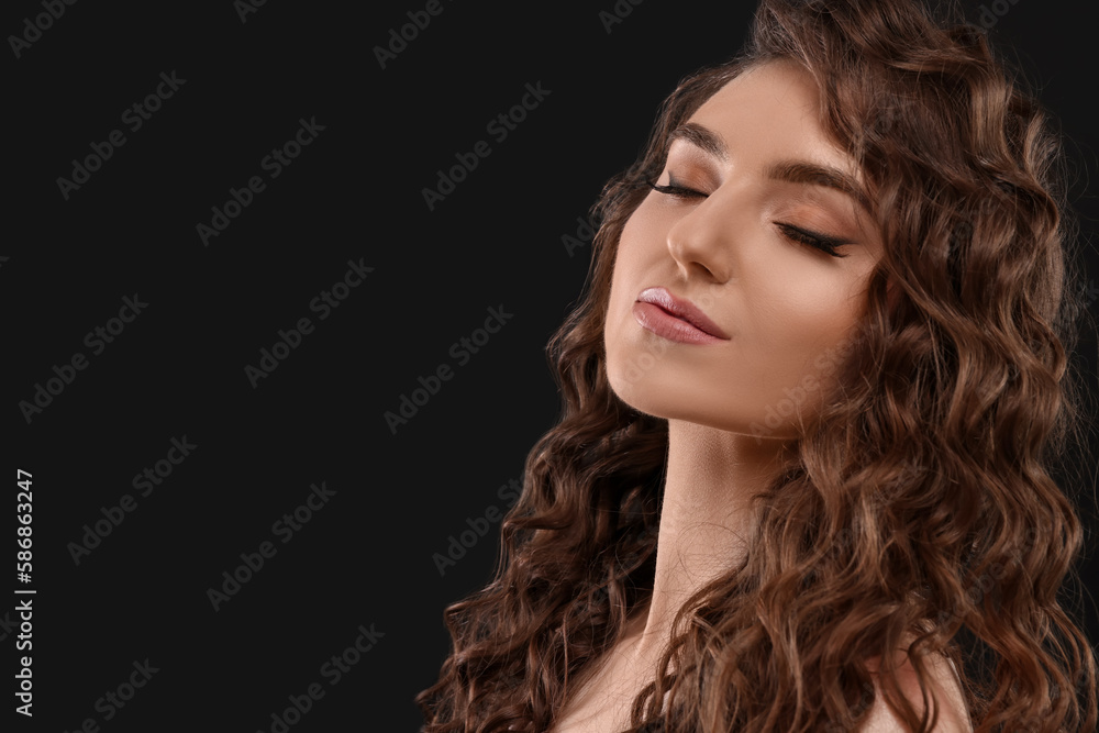 Beautiful young woman with long curly brown hair on black background, closeup. Space for text Beautiful young woman with long curly brown hair on black background, closeup. Space for text