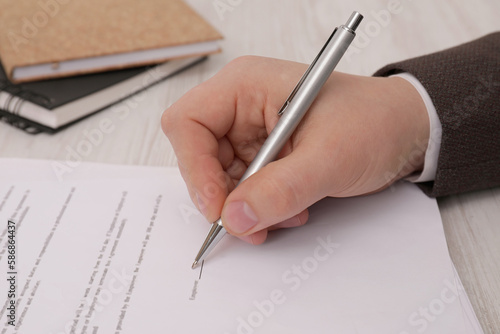 Man signing document at wooden table, closeup