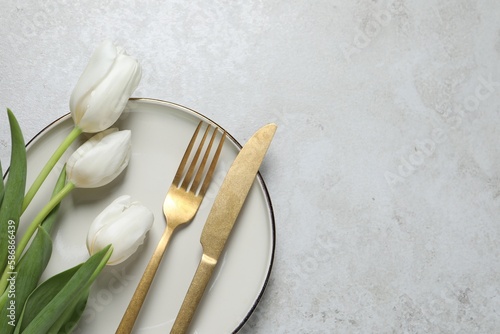 Stylish table setting with cutlery and flowers on grey background  flat lay. Space for text