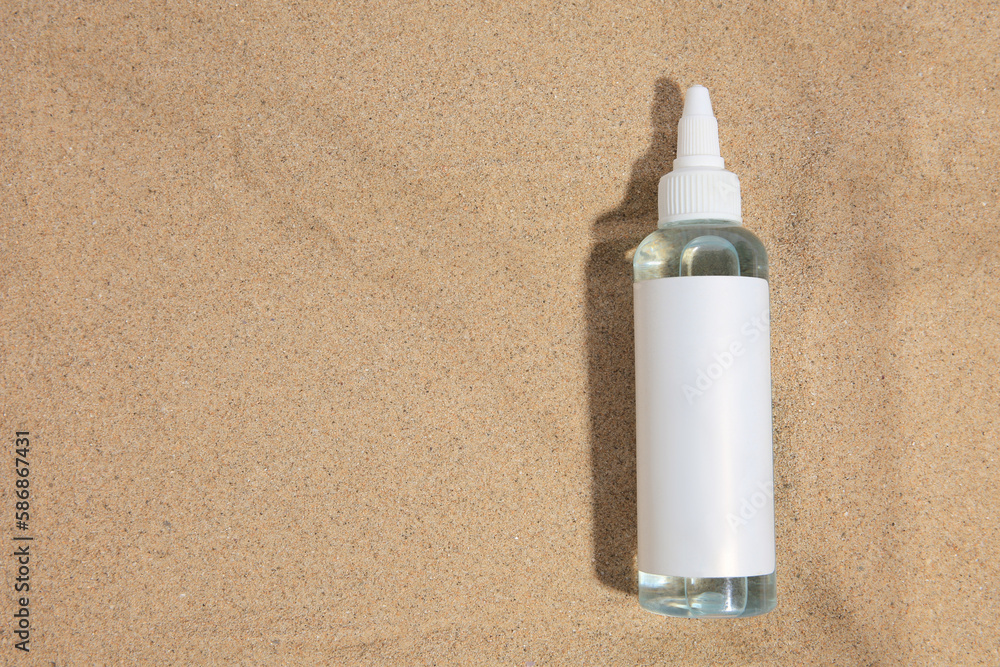 Bottle with serum on sand, top view and space for text. Cosmetic product Bottle with serum on sand, top view and space for text. Cosmetic product