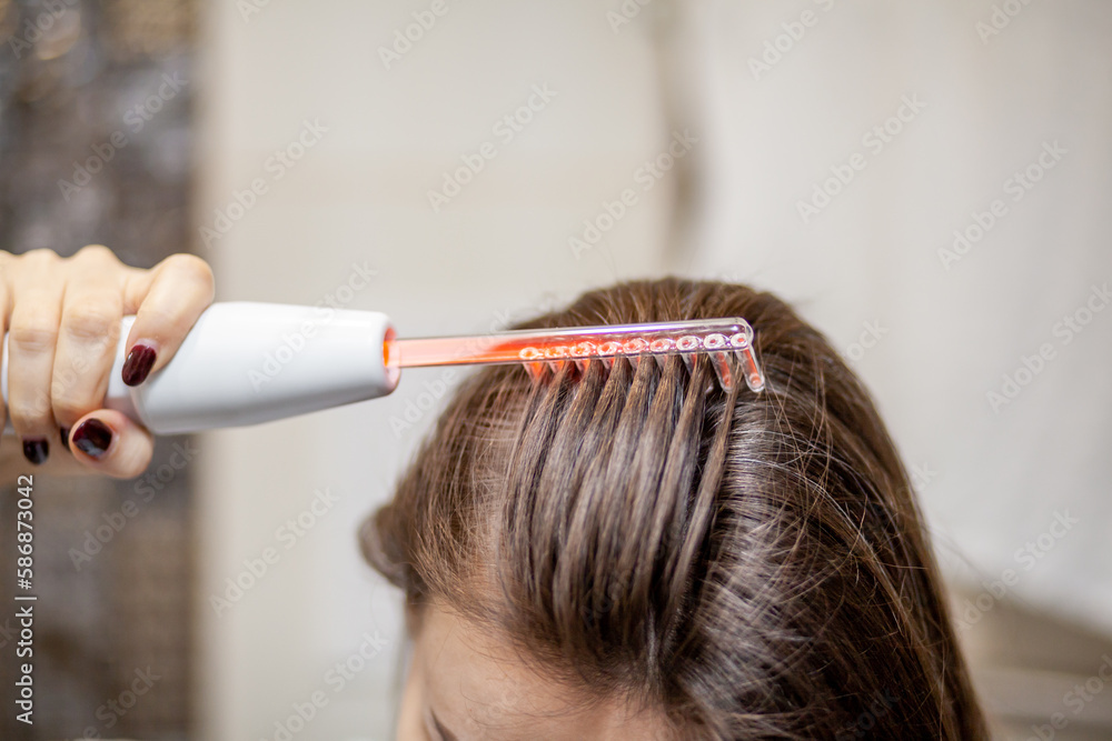 Naklejka premium Woman uses darsonval for massage head's skin. Receiving electric darsonval facial massage procedure. Face Beauty Treatment. Darsonval Therapy Using High Frequency D'Arsonval, Skin Care Device . 
