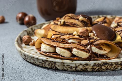 Homemade thin crepes with chocolate spread, banana and hazelnuts. breakfast or dessert. banner, menu, recipe place for text, top view