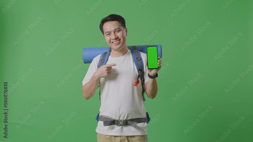 Asian Male Hiker With Mountaineering Backpack Smiling And Pointing To Mock Up Green Screen Smartphone While Standing On Green Screen Background In The Studio
Asian Male Hiker With Mountaineering Backpack Smiling And Pointing To Mock Up Green Screen Smartphone While Standing On Green Screen Background In The Studio