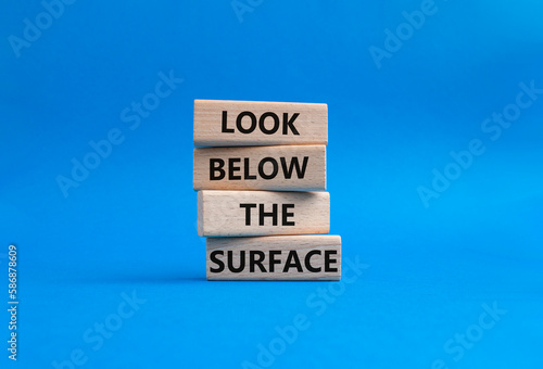 Look below the surface symbol. Concept word Look below the surface on wooden blocks. Beautiful blue background. Business and Look below the surface concept. Copy space
