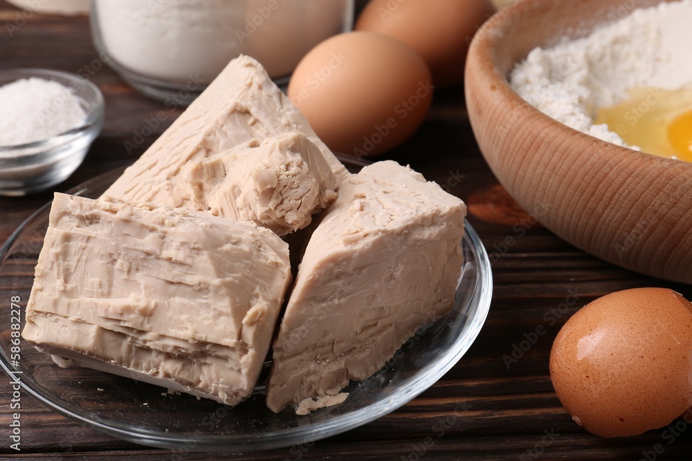 Compressed yeast, eggs, salt and flour on wooden table, closeup Compressed yeast, eggs, salt and flour on wooden table, closeup