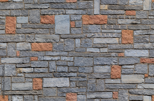 Endless pattern of a stone wall with gray and reddish stone blocks. photo