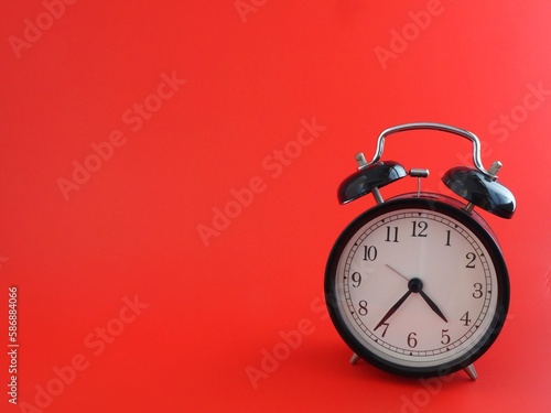 alarma reloj despertador retro negro aislado sobre fondo rojo a la derecha con espacio para texto