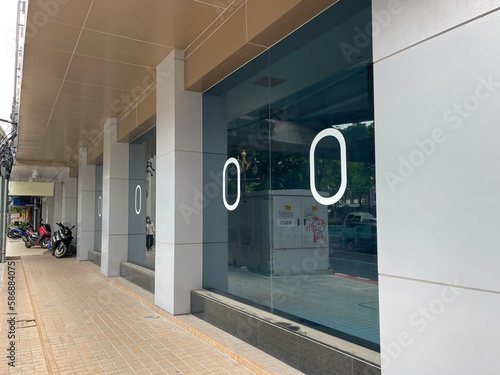 Stylish glass door in modern urban building. Bangkok city, the capital of Thailand. Empty street. Closed door. Modern design, entrance group to the office space, shop, showroom. Front view, facade.