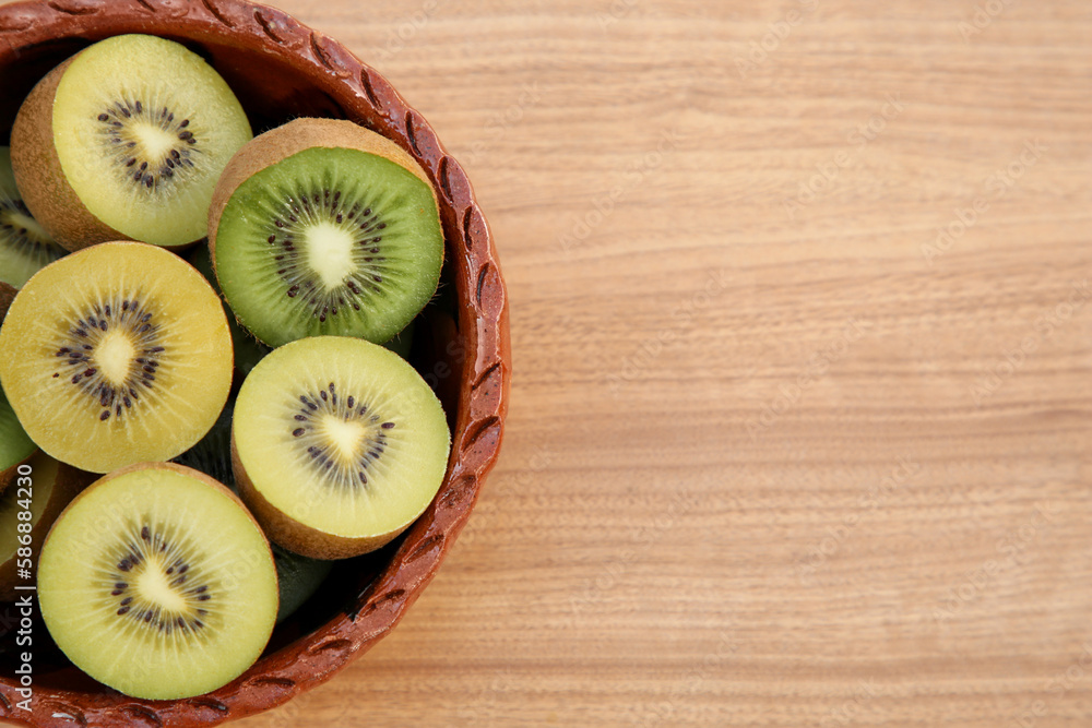Bowl of many cut fresh kiwis on wooden table, top view. Space for text Bowl of many cut fresh kiwis on wooden table, top view. Space for text