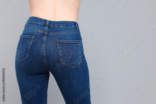 Fototapeta Naklejka Na Ścianę i Meble -  Woman in stylish jeans on grey background, closeup. Space for text