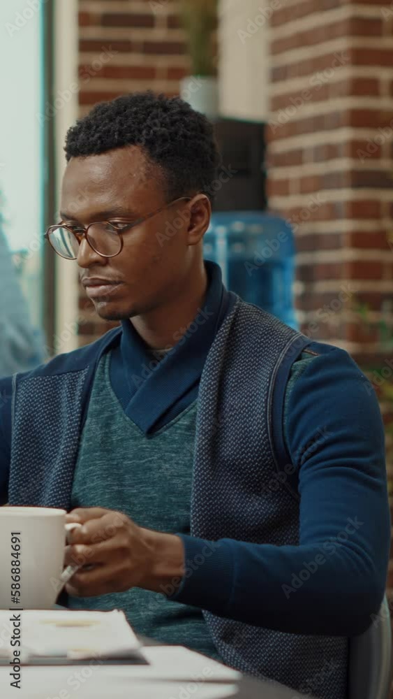 Vertical video: African american man planning reports, working with executive data analytics in coworking space. Business manager reading official company statistics before making important decisions. Vertical video: African american man planning reports, working with executive data analytics in coworking space. Business manager reading official company statistics before making important decisions.