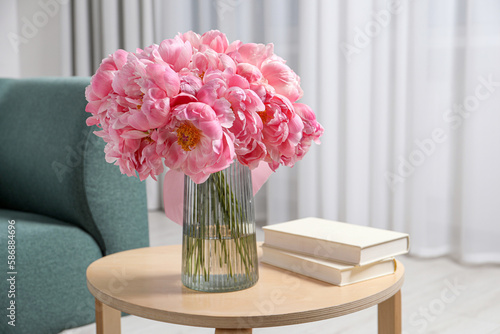Fototapeta Naklejka Na Ścianę i Meble -  Beautiful bouquet of pink peonies in vase and books on wooden table indoors