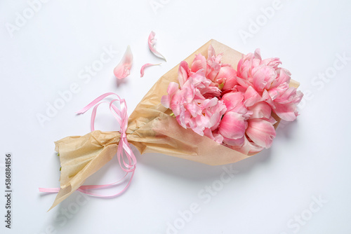 Beautiful bouquet of pink peonies wrapped in paper on white background, top view © New Africa