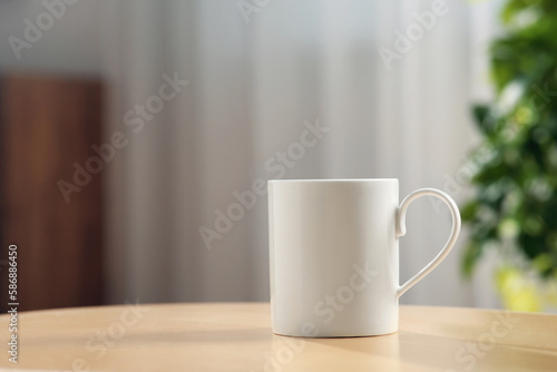 White mug on wooden table indoors. Mockup for design