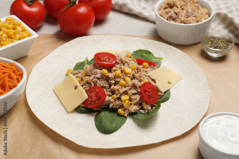 Delicious tortilla with tuna, vegetables and cheese on light table. Cooking shawarma Delicious tortilla with tuna, vegetables and cheese on light table. Cooking shawarma