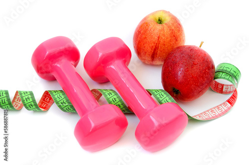 Red apple with dumbbell and measuring tape on white background.