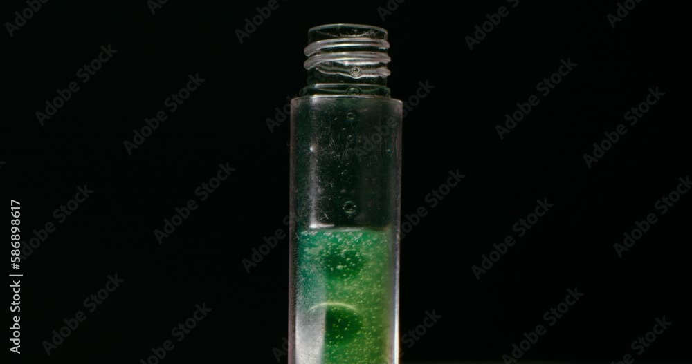 Green and transparent liquid being poured into a vial. Black background. Cinematic short. Green and transparent liquid being poured into a vial. Black background. Cinematic short.