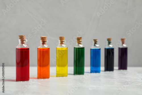 Glass bottles with different food coloring on light grey marble table