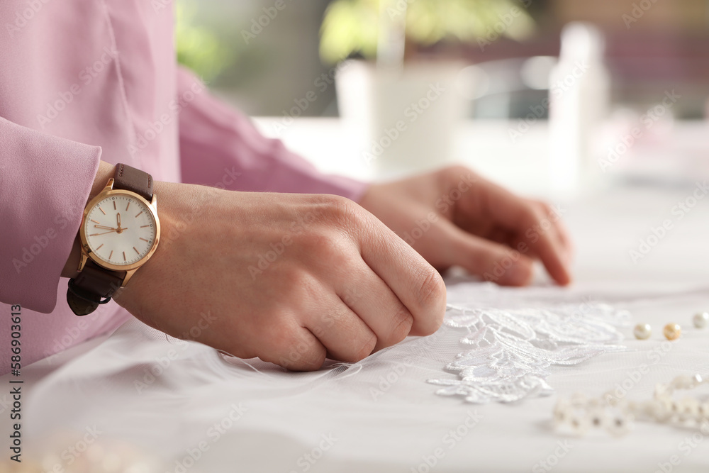 Obraz premium Dressmaker working with beautiful white lace at table in atelier, closeup