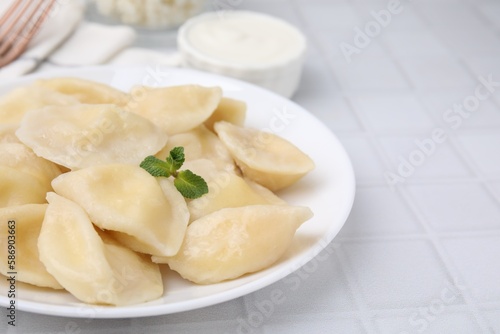 Plate of delicious dumplings (varenyky) with cottage cheese on white table, closeup