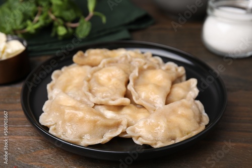 Plate of delicious dumplings (varenyky) with cottage cheese on wooden table, closeup