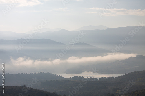 Pantano de Beniarrés con capas de montañas y niebla a contraluz 