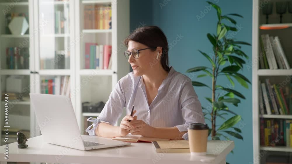 Beautiful mature woman working remotely on laptop, engaging in virtual communication with team, coach, manager. Professional video conference call at home or stylish office. Collaboration productivity Beautiful mature woman working remotely on laptop, engaging in virtual communication with team, coach, manager. Professional video conference call at home or stylish office. Collaboration productivity