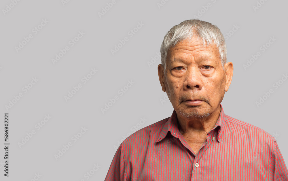 Portrait of an elderly Asian man in a shirt looking at the camera with a smile while standing on a gray background Portrait of an elderly Asian man in a shirt looking at the camera with a smile while standing on a gray background