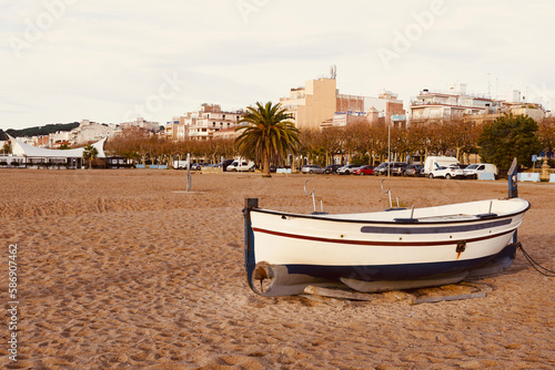 Calella beach at sunrise time with boats on the sand near the seashore town in the background. Vacation place near the tourist Costa Brava. Barcelona, Spain. Beaches of Maresme, Catalan coast. photo
