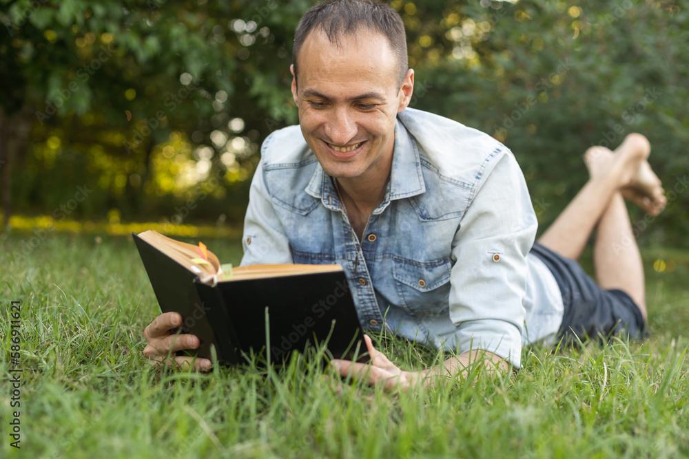 Obraz premium a man reads the Bible on the grass at a park