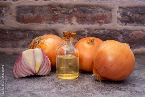 Onions on wooden table and onion oil in glass bottle . Onion - the new trendy ingredient in skin and hair care products.