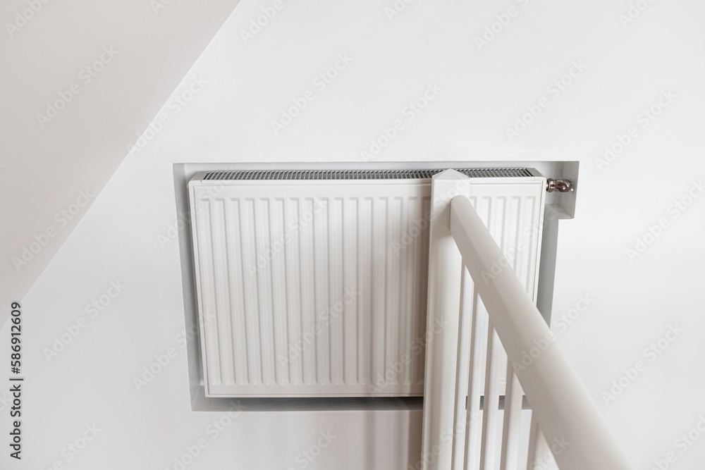 White hot water heater radiator built inside drywall indoors at home