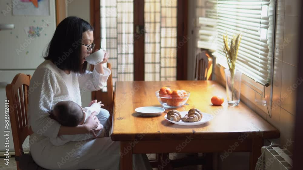 Classic home scene of a woman drinking coffee while breastfeeding her