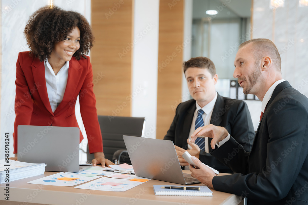 Mature business leader consultant talking to team of diverse colleagues listening to white CEO. Group project manager negotiating in the boardroom at a meeting. Mature business leader consultant talking to team of diverse colleagues listening to white CEO. Group project manager negotiating in the boardroom at a meeting.
