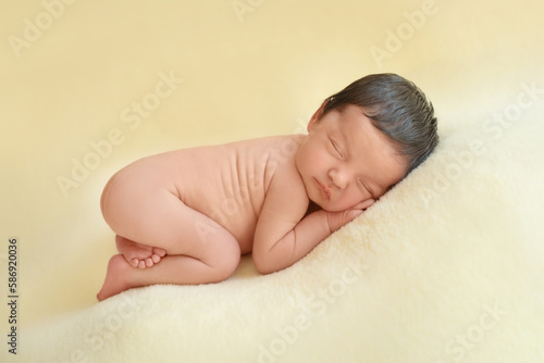 Newborn baby infant with dark hair lying on side sleeping . Cute little Middle eastern child on blanket. Tranquil scene copy space for advertisement