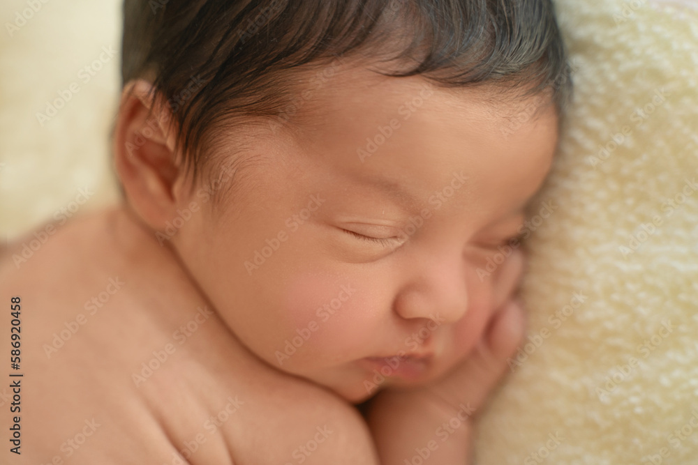 Newborn baby infant with dark hair lying on side sleeping . Cute little Middle eastern child on blanket. Tranquil scene copy space for advertisement Newborn baby infant with dark hair lying on side sleeping . Cute little Middle eastern child on blanket. Tranquil scene copy space for advertisement
