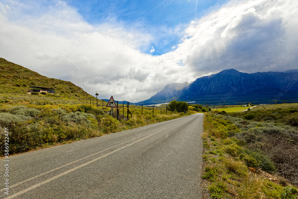 Naklejka premium A view along a road towards high mountains in the distance, near Worcester, South Africa.