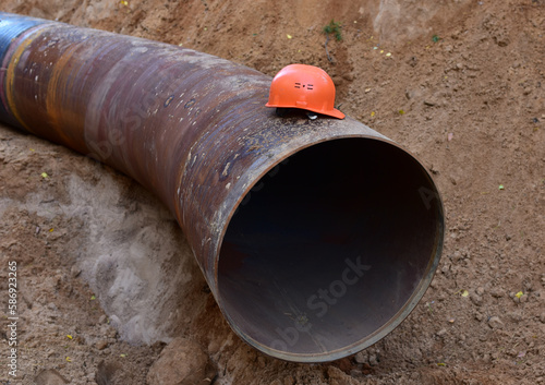 Safety helmet on a pipe in a trench during the construction of a gas pipeline. Saviour Tough Hat during workers' strike. Natural Gas and Crude oil Transmission in pipe to LNG plant. Petrochemical pipe