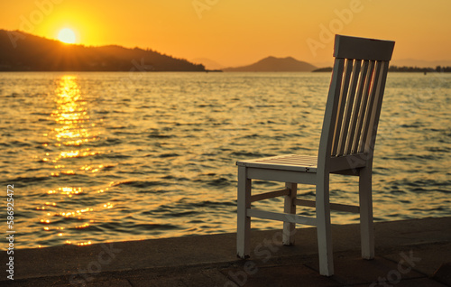 Sunset on the promenade by the sea  old chair in a cafe near the sea water on the Aegean coast  warm spring sunset  vacation time