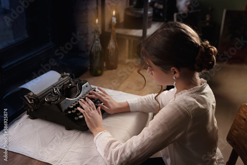 Young female writer writes a novel on a printing machine in an art studio