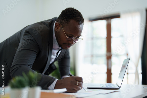 middle aged man American African using computer laptop with planning working on financial document, tax, exchange, accounting and Financial advisor. auditor or audit concepts