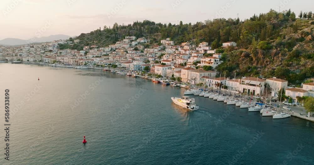 Poros island, Greece. Sailing yacht in marina at Aegean sea Aerial view of drone slide on panorama down authentic houses of sailing yachts high mountains of sea harbors summer. Travel. Tourism Poros island, Greece. Sailing yacht in marina at Aegean sea Aerial view of drone slide on panorama down authentic houses of sailing yachts high mountains of sea harbors summer. Travel. Tourism