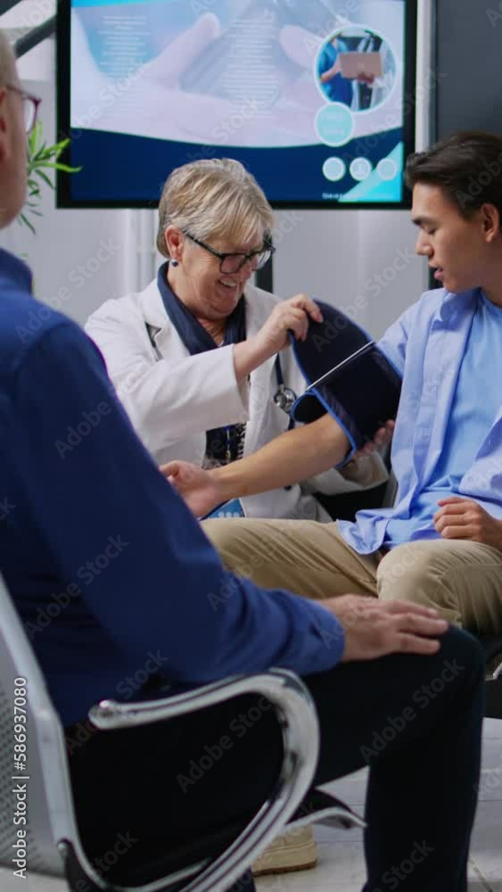 Vertical video: Senior specialist doing cardiology exam with tonometer to measure patient hypertension and hypotension, checking blood pressure with instrument. Doctor measuring asian man high or low Vertical video: Senior specialist doing cardiology exam with tonometer to measure patient hypertension and hypotension, checking blood pressure with instrument. Doctor measuring asian man high or low